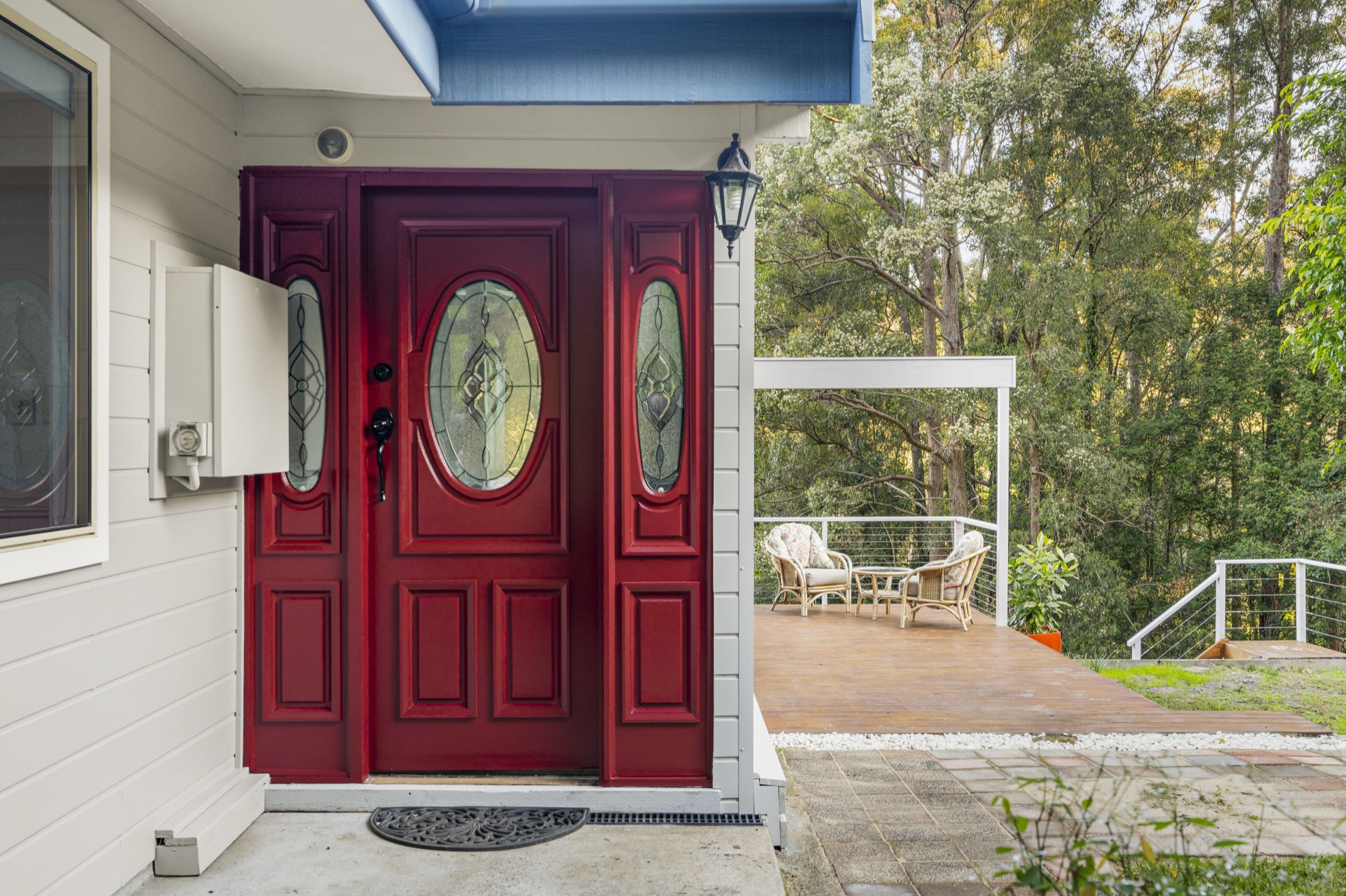 Red front door with wicker chairs on the deck