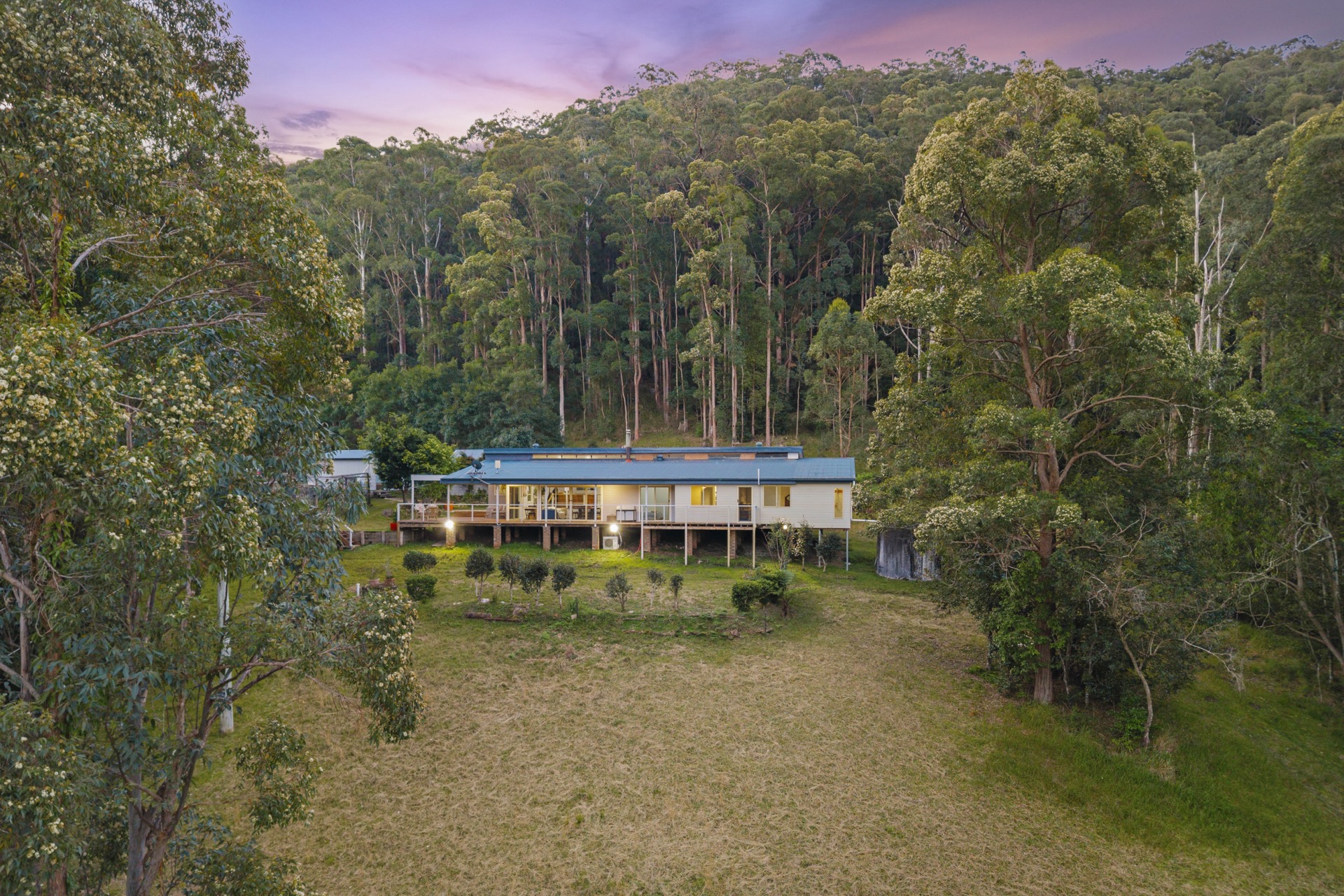 32 Geerings Road, Martinsville - freshly renovated home with large decking on 3 sides at dusk, surrounded by forest